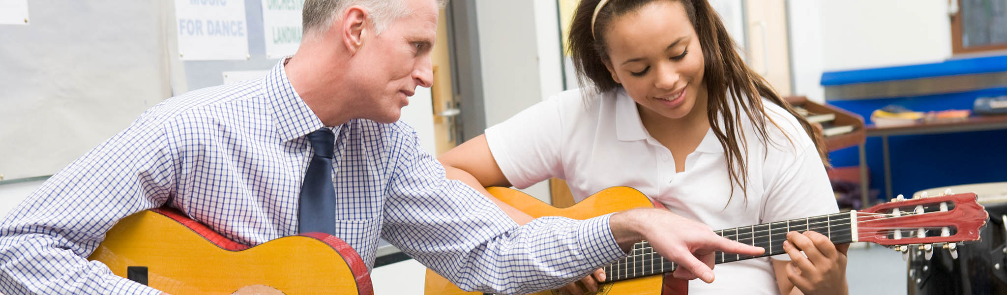 Guitar instructor teaching guitar student