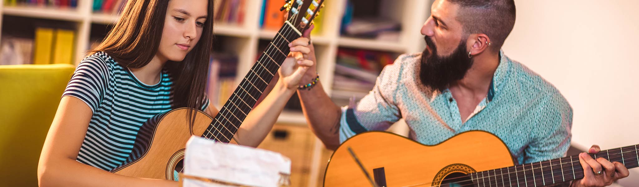 Guitar teacher teaching the girl guitar for lessons.