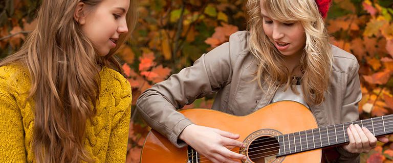 Everyday Financing Programs girl playing guitar and one girl listening